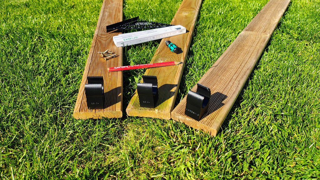 Clipper Jump Unterfahrschutz an drei Terrassendielen – Nahaufnahme der montierten Clips